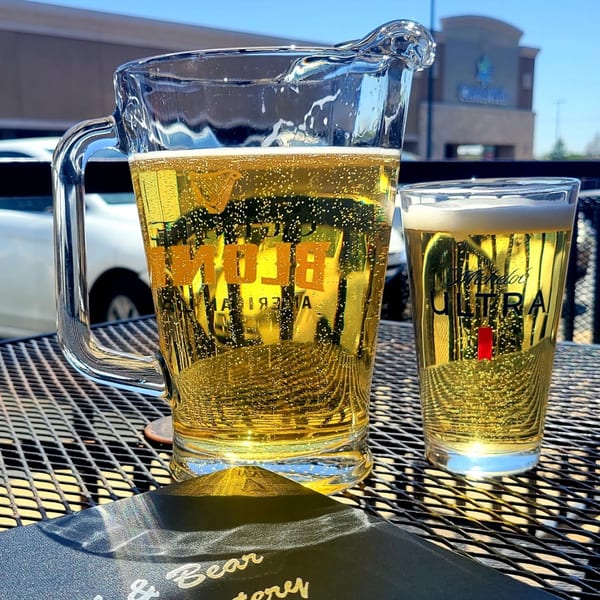 A pitcher and glass of Michelob Ultra beer on a patio table at Bull & Bear Eatery.