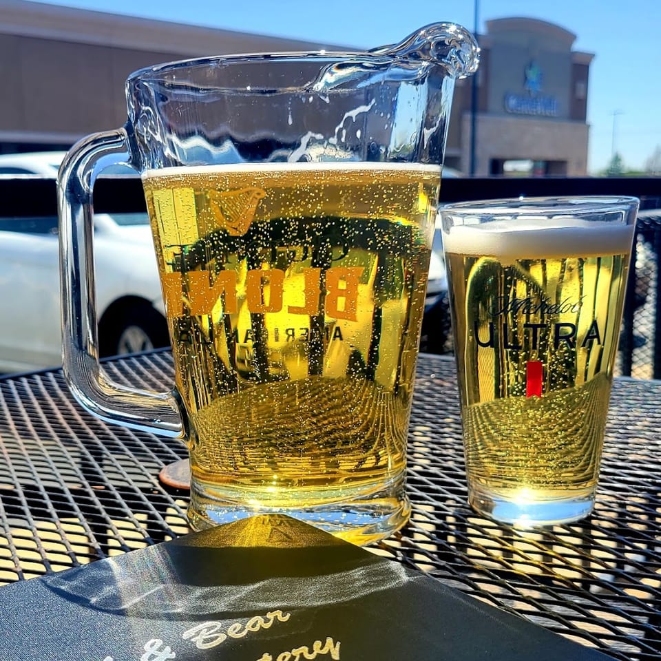 A pitcher and glass of Michelob Ultra beer on a patio table at Bull & Bear Eatery.